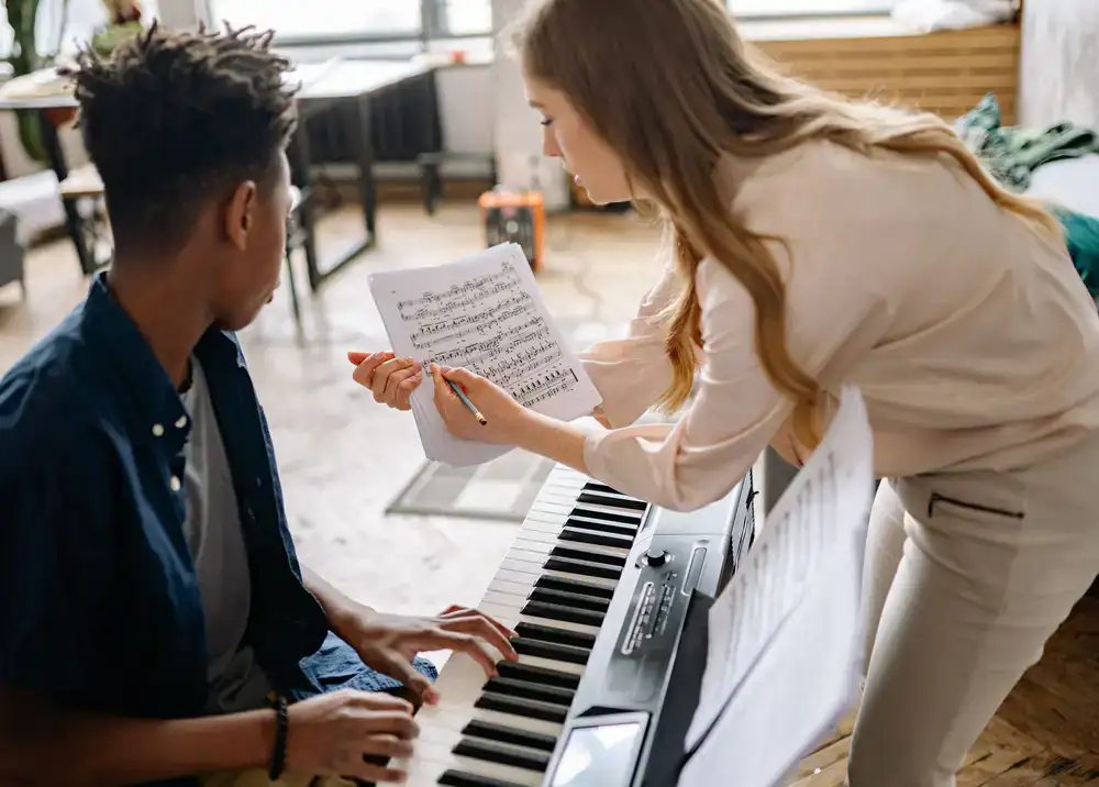 Staff member assisting a young student with a keyboard